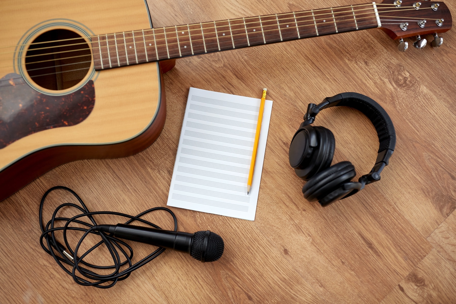 A songwriter's handwritten lyric sheet beside an acoustic guitar