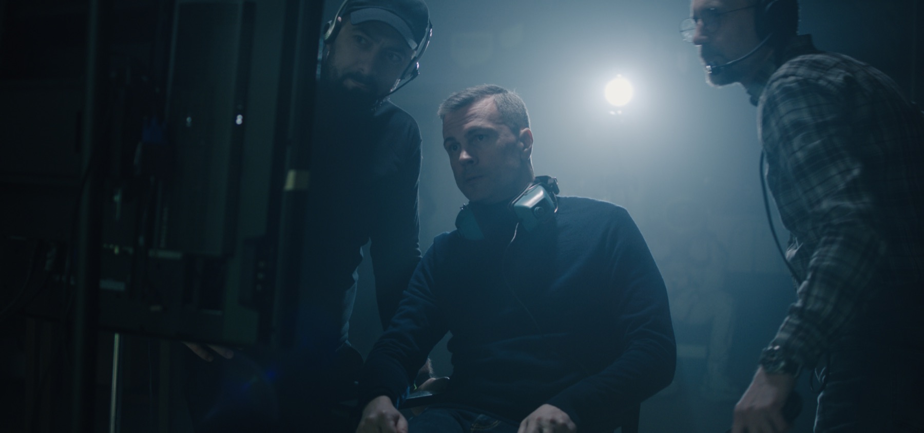 A film director reviewing footage on a monitor beside a camera operator on set