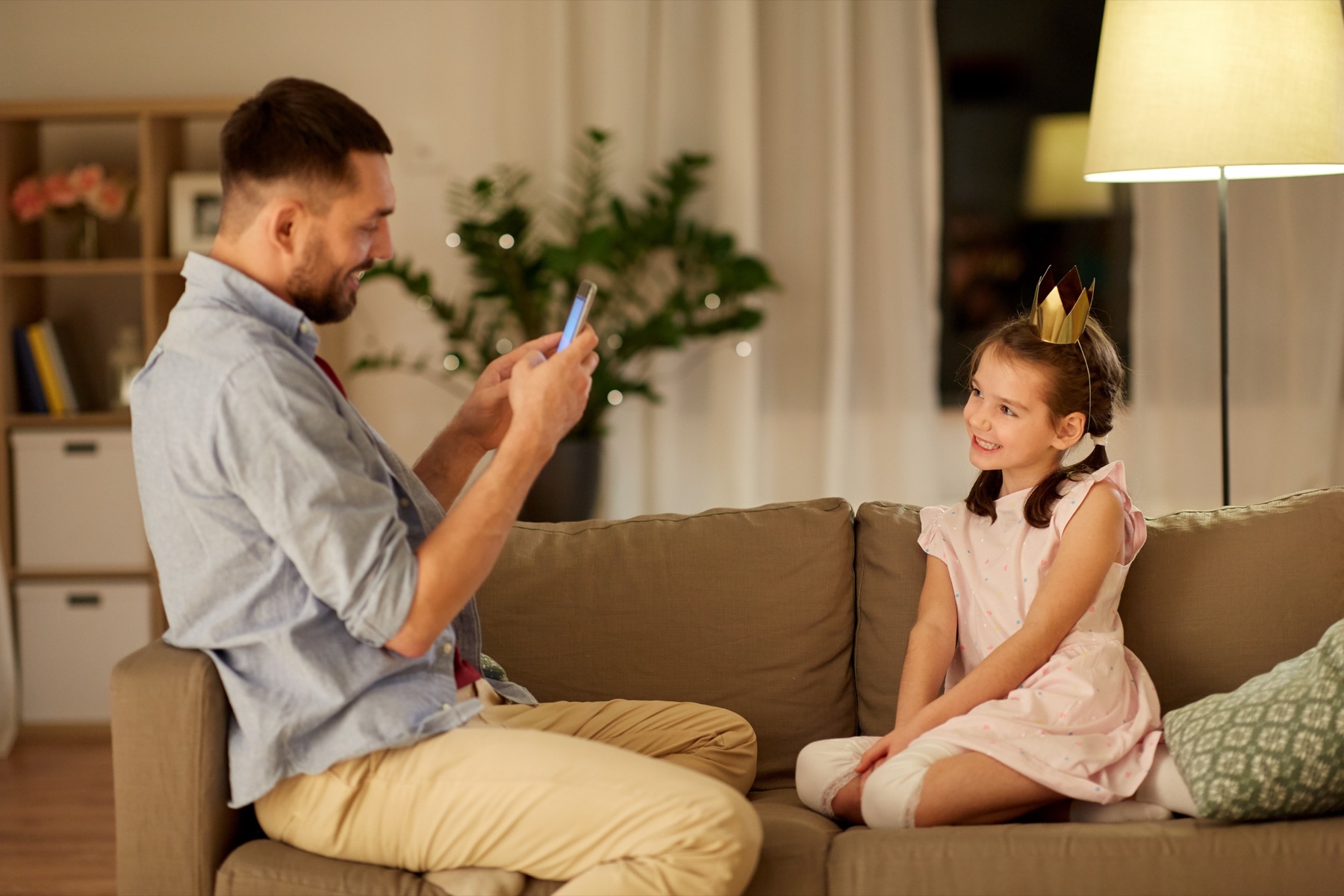 A parent recording a toddler dancing in a living room on a smartphone