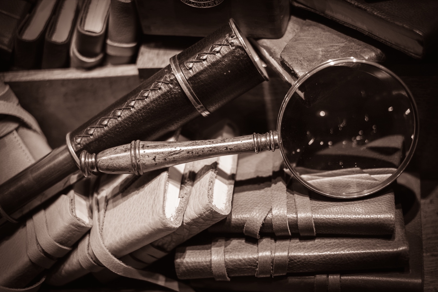A deerstalker hat and magnifying glass on an old book, evoking Sherlock Holmes