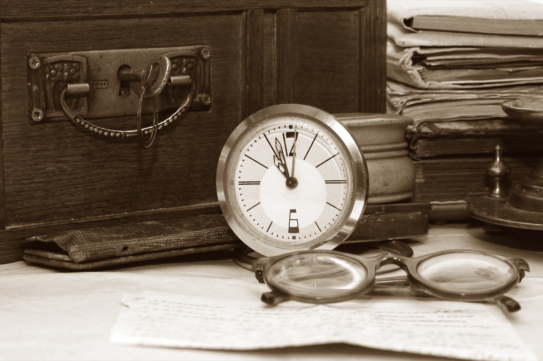 An antique ledger book open to ruled accounting columns beside a quill pen