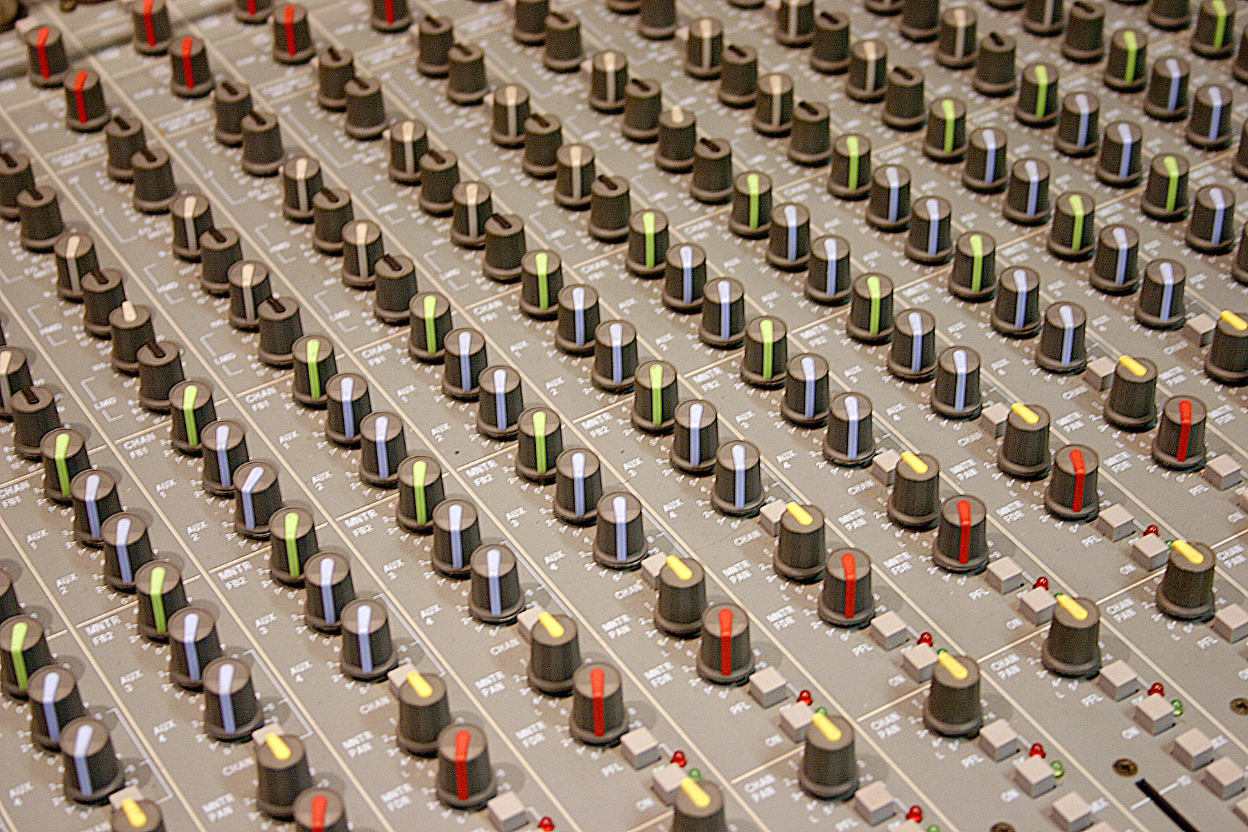 A recording studio mixing console with faders and knobs
