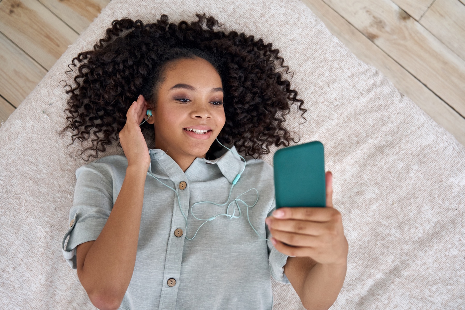 A smartphone displaying a music streaming app beside headphones