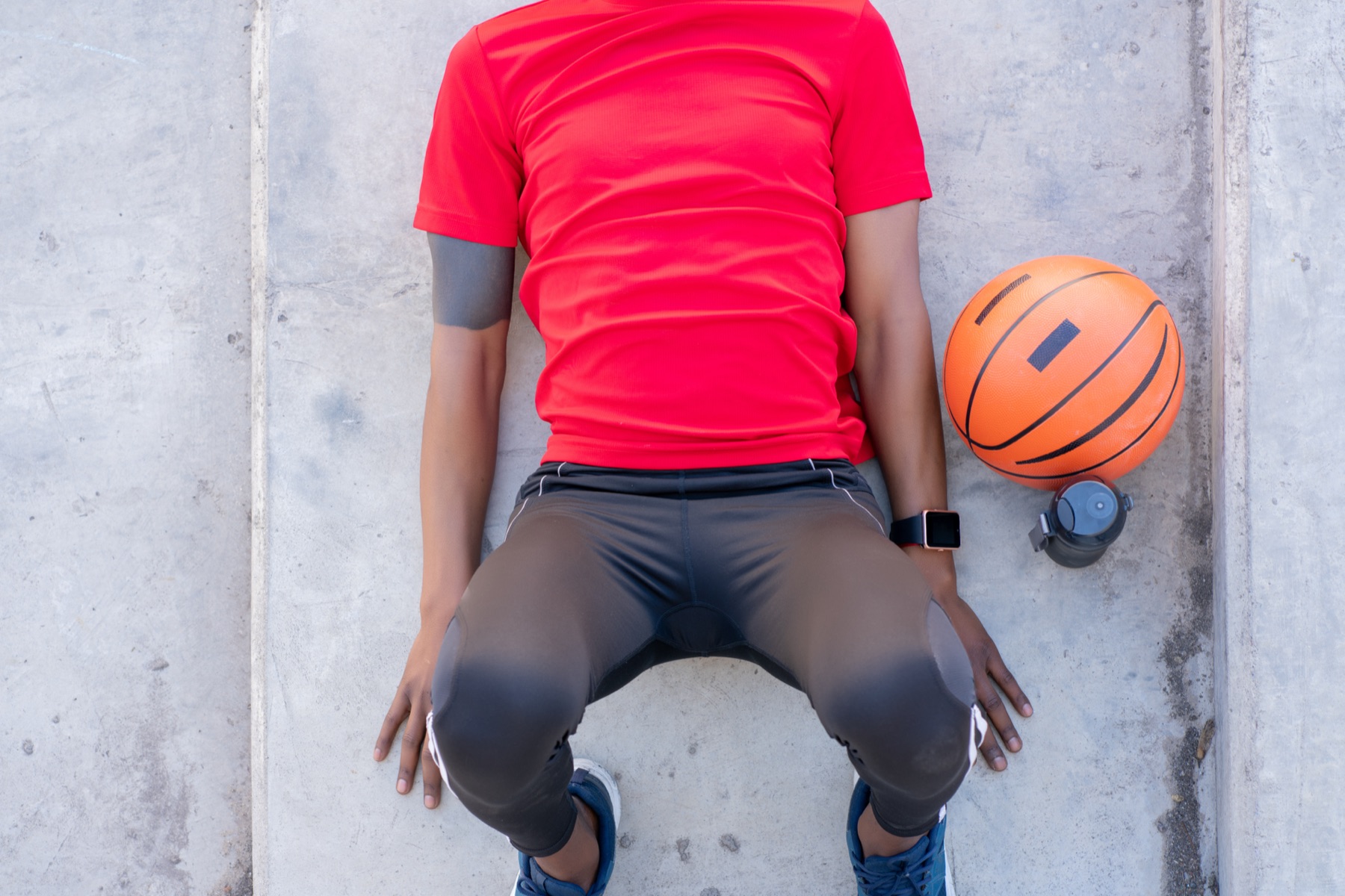 A basketball player's tattooed arm gripping a basketball under arena lighting