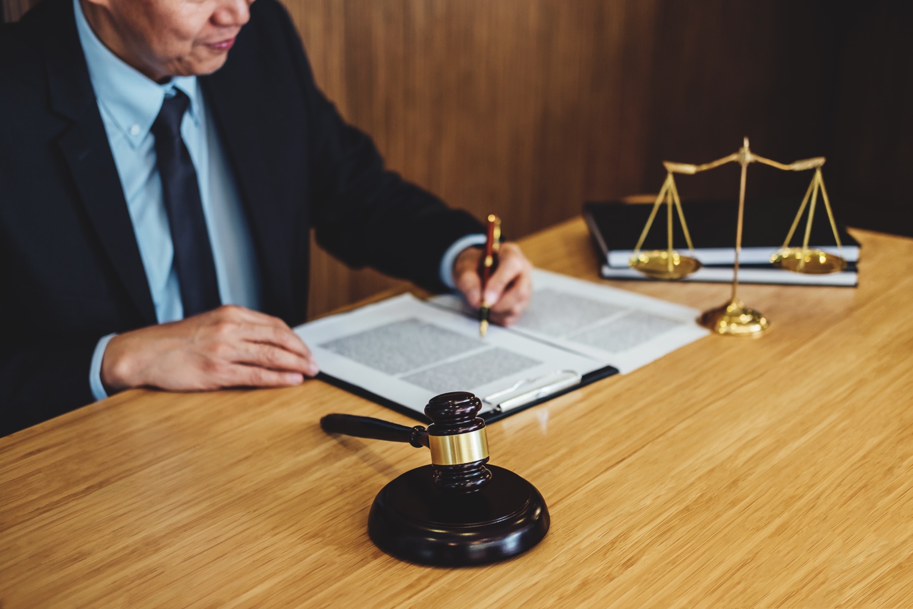 A judge's bench with a gavel and patent documents under a desk lamp