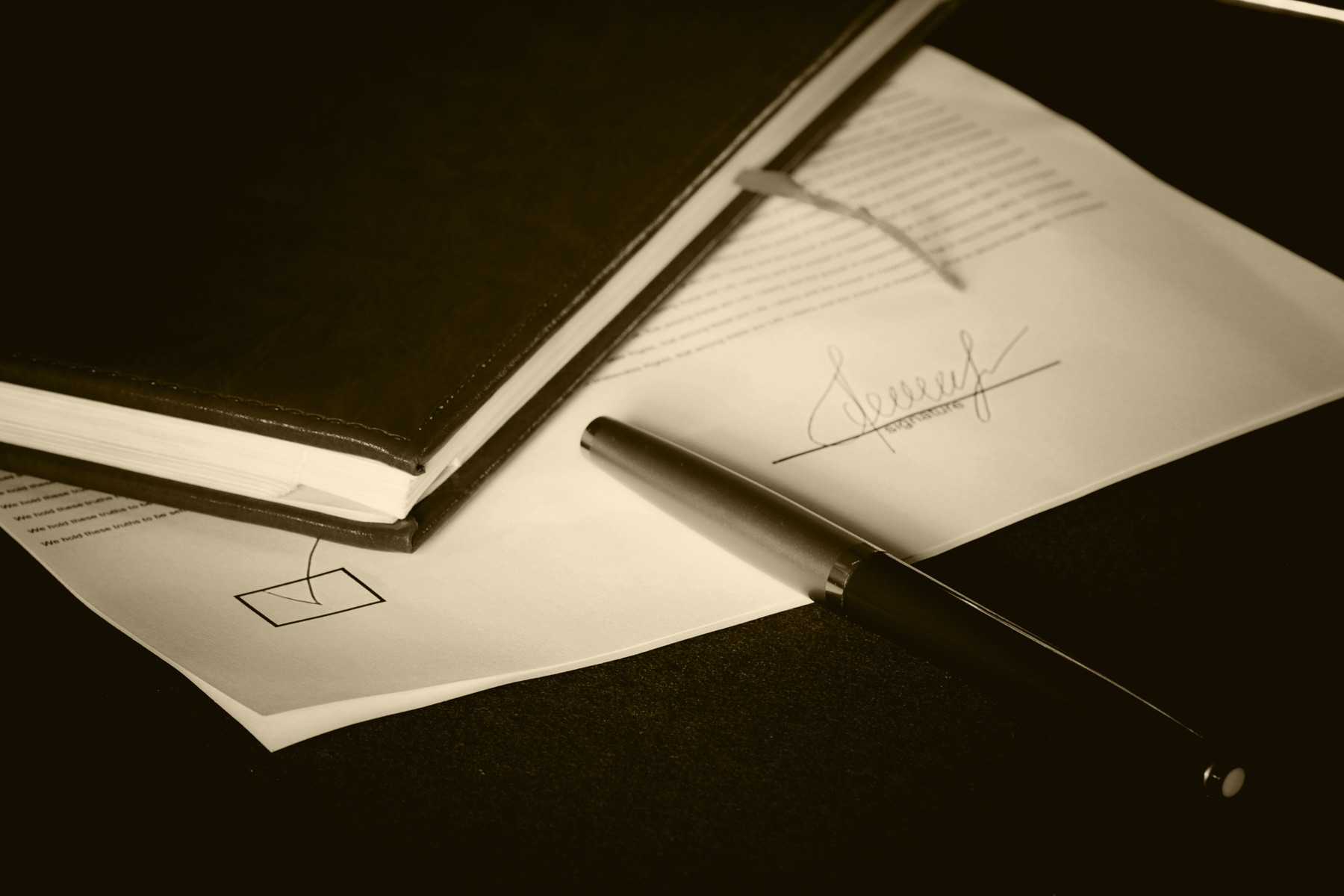 A close-up of a statute book open to text with a pen resting on the page