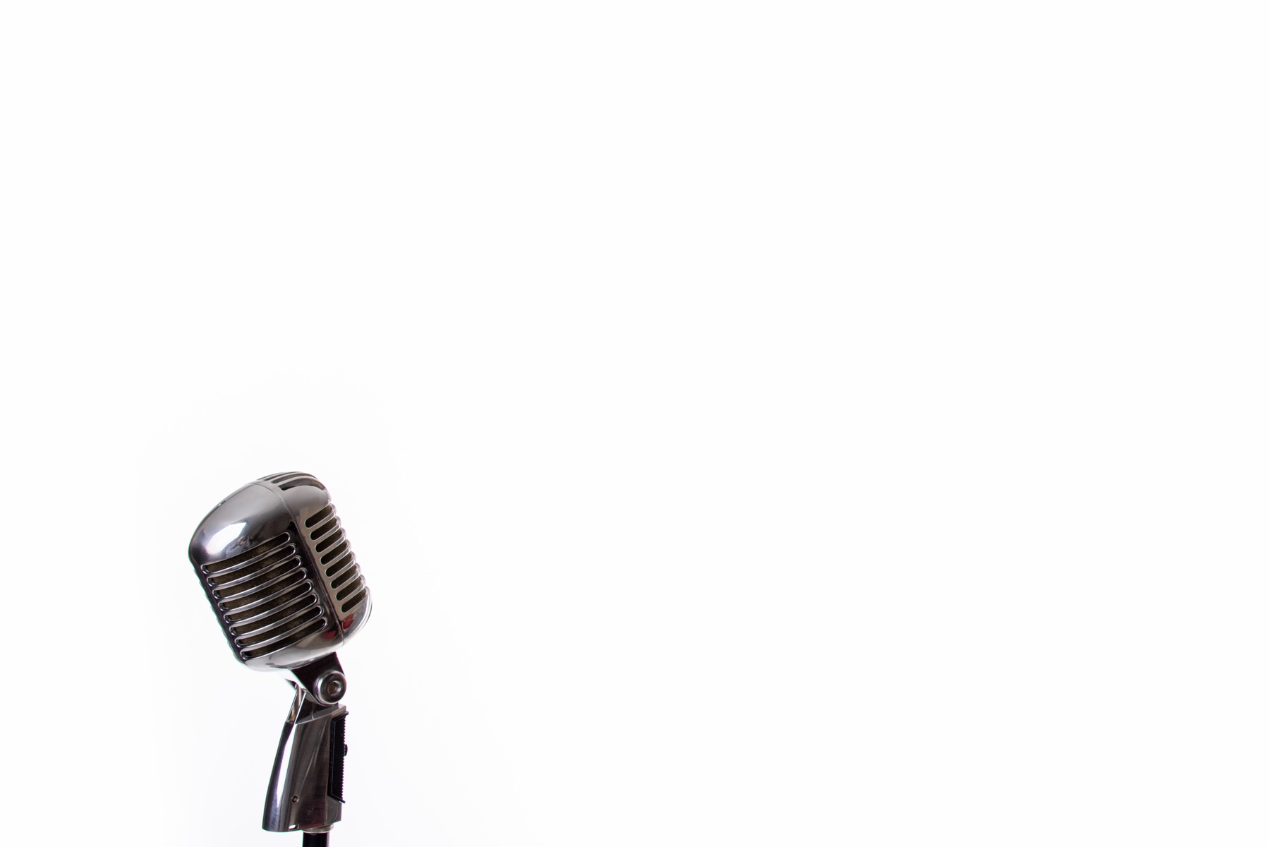 A vintage microphone on a stand in a recording studio under warm light