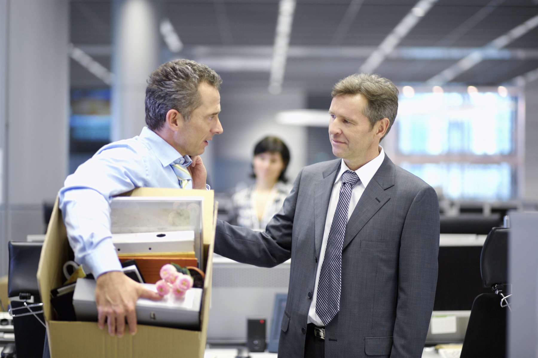 A corporate executive carrying a box of belongings out of an office