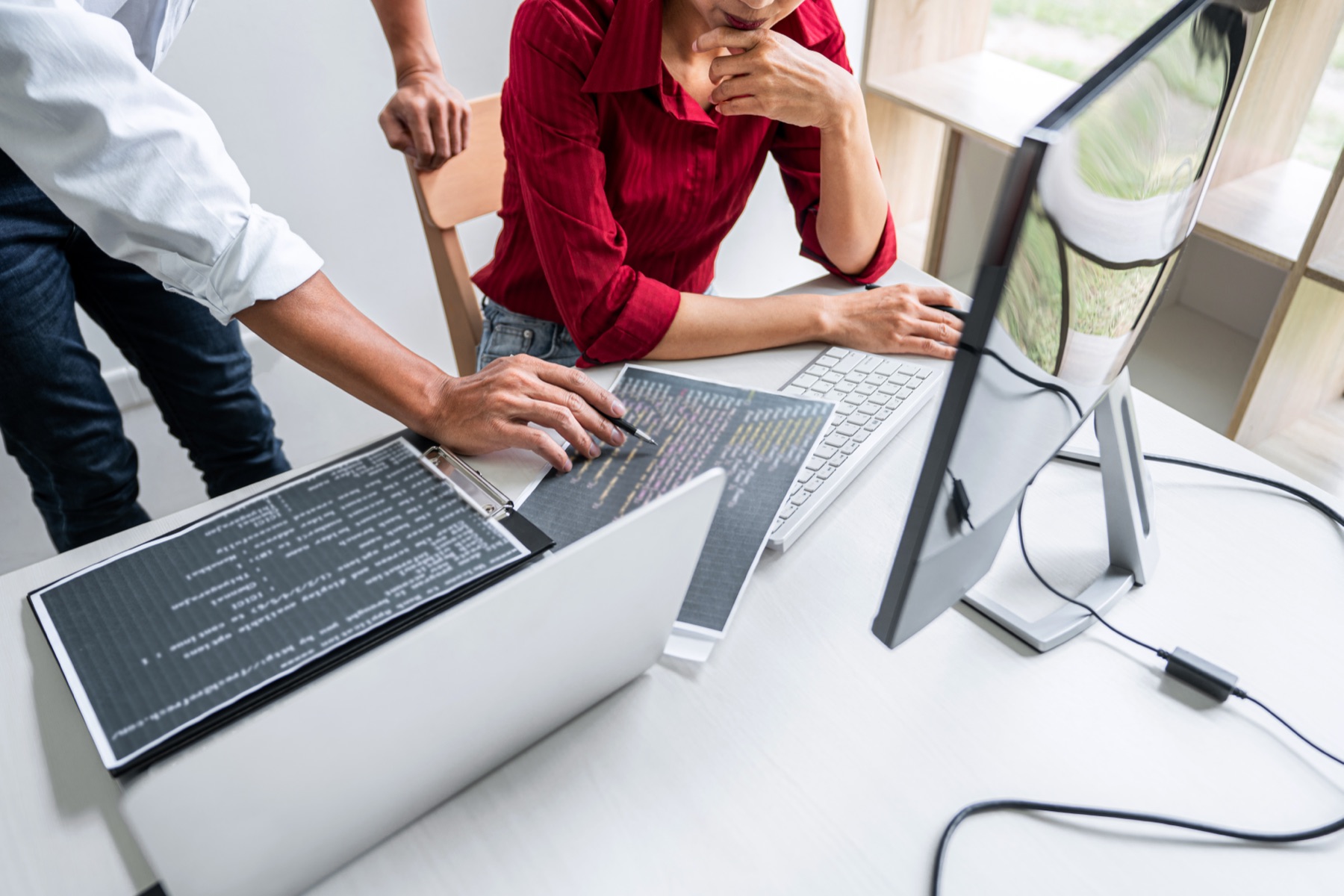 A software developer reviewing source code on multiple monitors