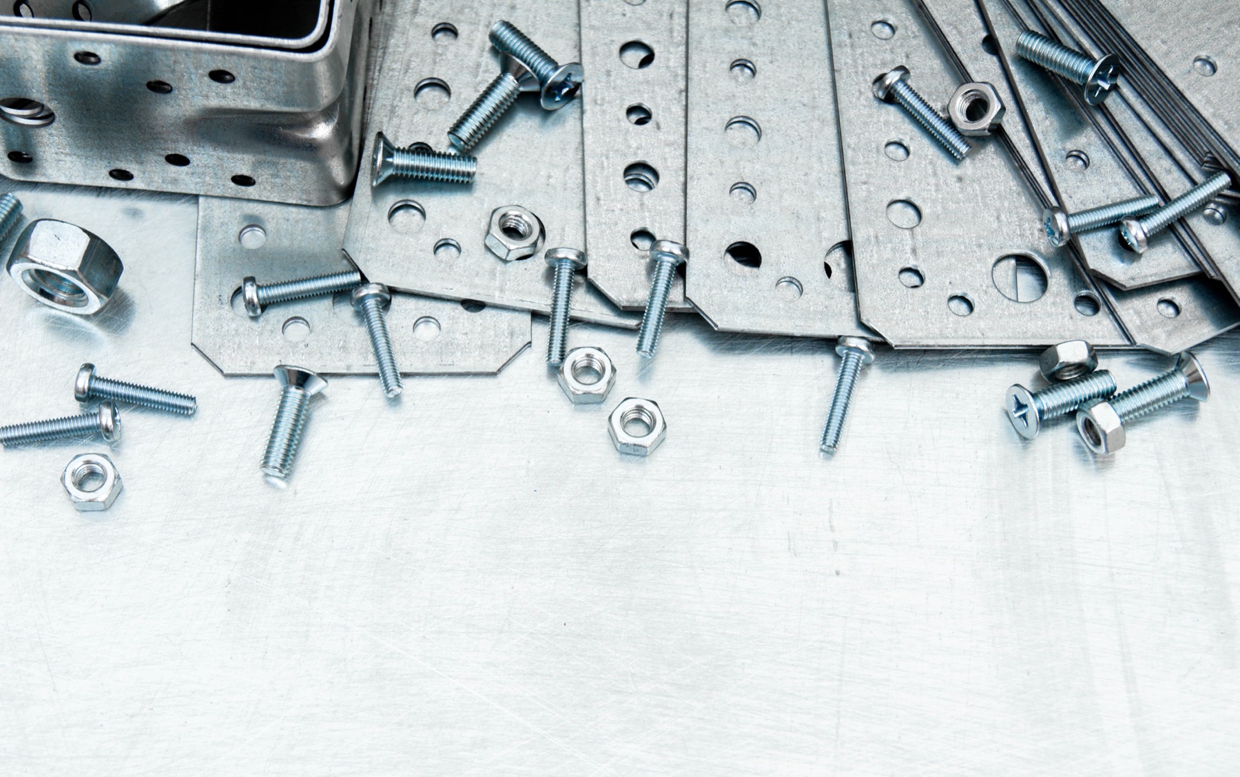 Rows of metal fasteners and screws on an industrial workbench