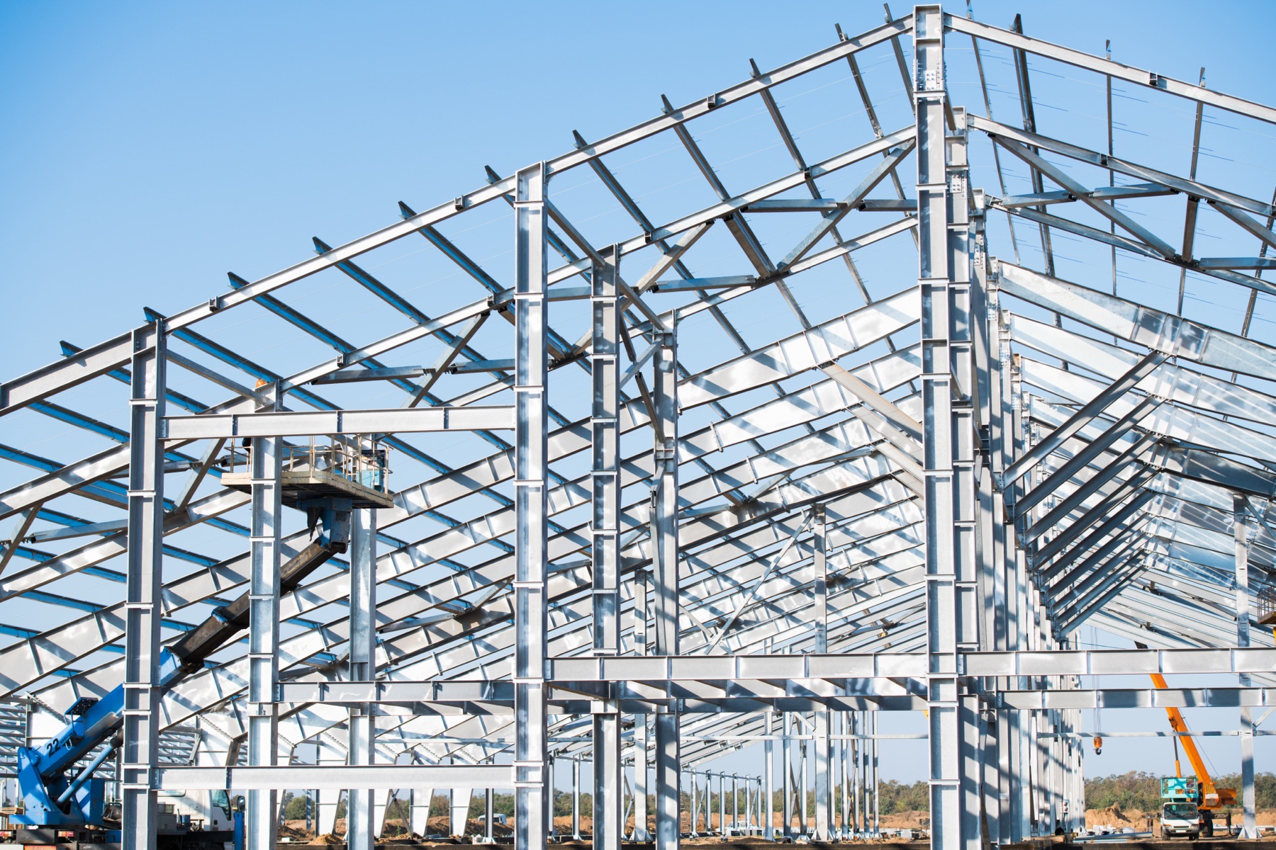Pre-engineered steel building frame under a clear sky